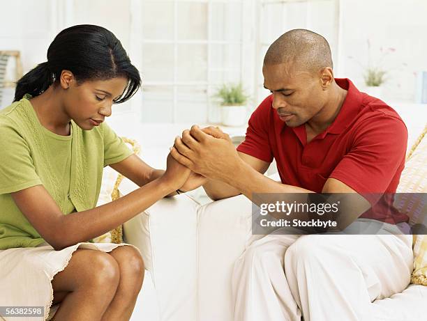 mid adult couple holding hands and praying - couple praying stock pictures, royalty-free photos & images