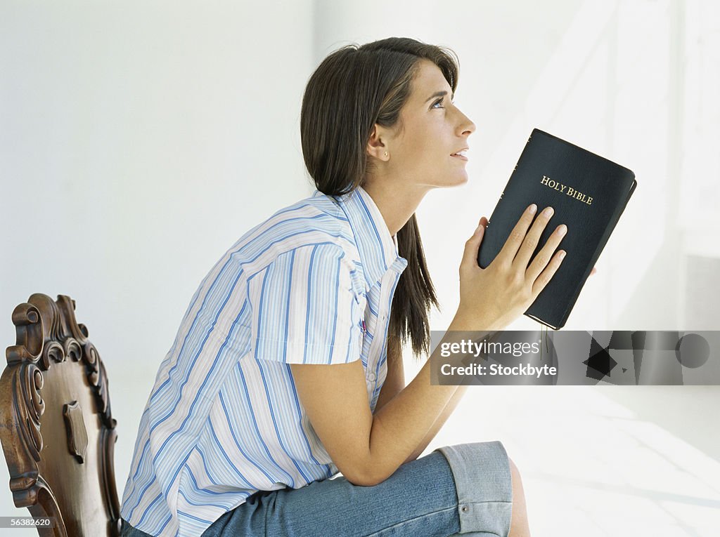 Side profile of a teenage girl sitting on a chair holding the bible