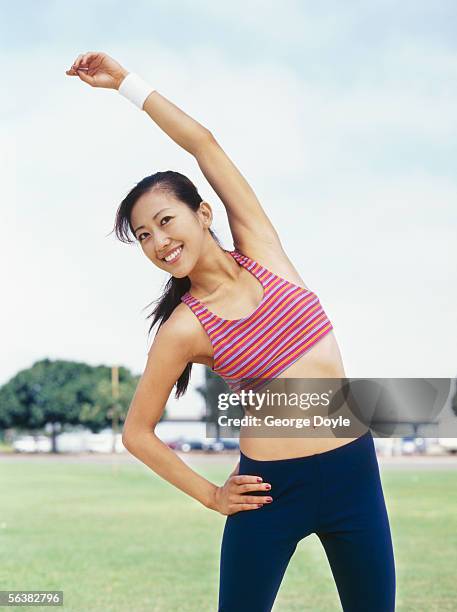 young woman exercising on a lawn - hip stretch vertical stock pictures, royalty-free photos & images