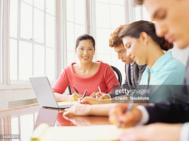 four business executives sitting around a table in an office - portrait man suit smiling light background stock pictures, royalty-free photos & images