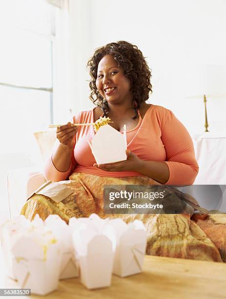 mid adult woman holding a takeaway and a pair of chopsticks - bulimie stock-fotos und bilder