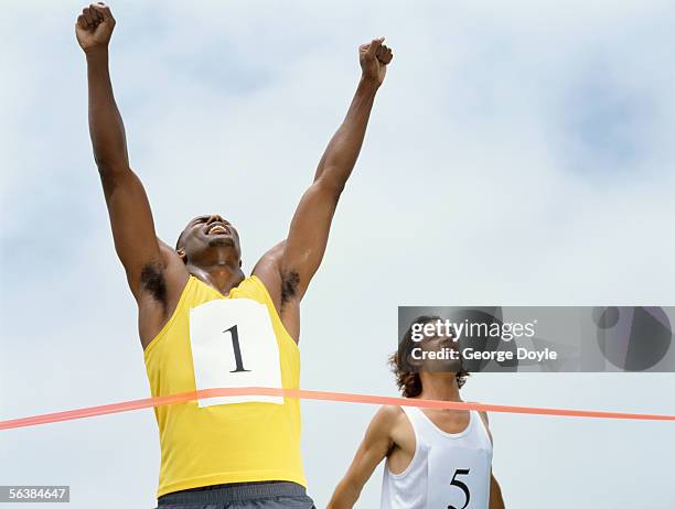 low angle view of male athlete crossing the finish line - 1 2 finale stock pictures, royalty-free photos & images