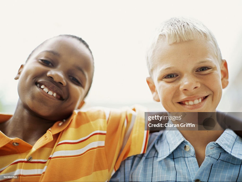 Portrait of two boys standing with their arms around