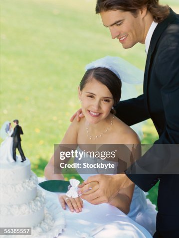 High angle view of a newlywed couple cutting a wedding cake High angle view of a newlywed couple cutting a wedding cake
