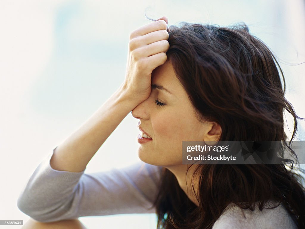 Side profile of a young woman holding her head in her hand