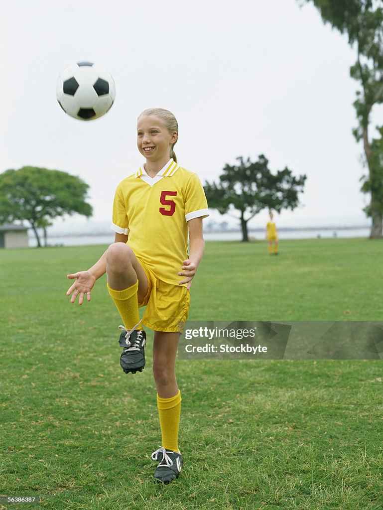 Girl practicing with a soccer ball in a field