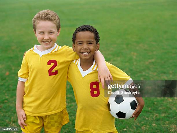 portrait of two boys standing with a soccer ball in a field - fußball 2 jungs stock-fotos und bilder