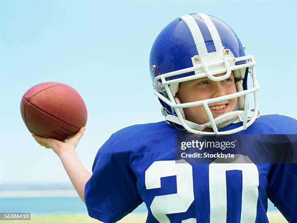 close-up of a boy wearing a helmet holding a football - american football strip stock pictures, royalty-free photos & images