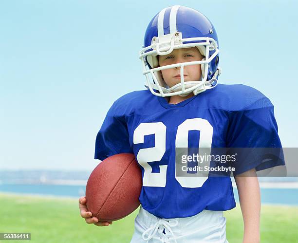portrait of a boy wearing a helmet holding a football - american football uniform stock pictures, royalty-free photos & images