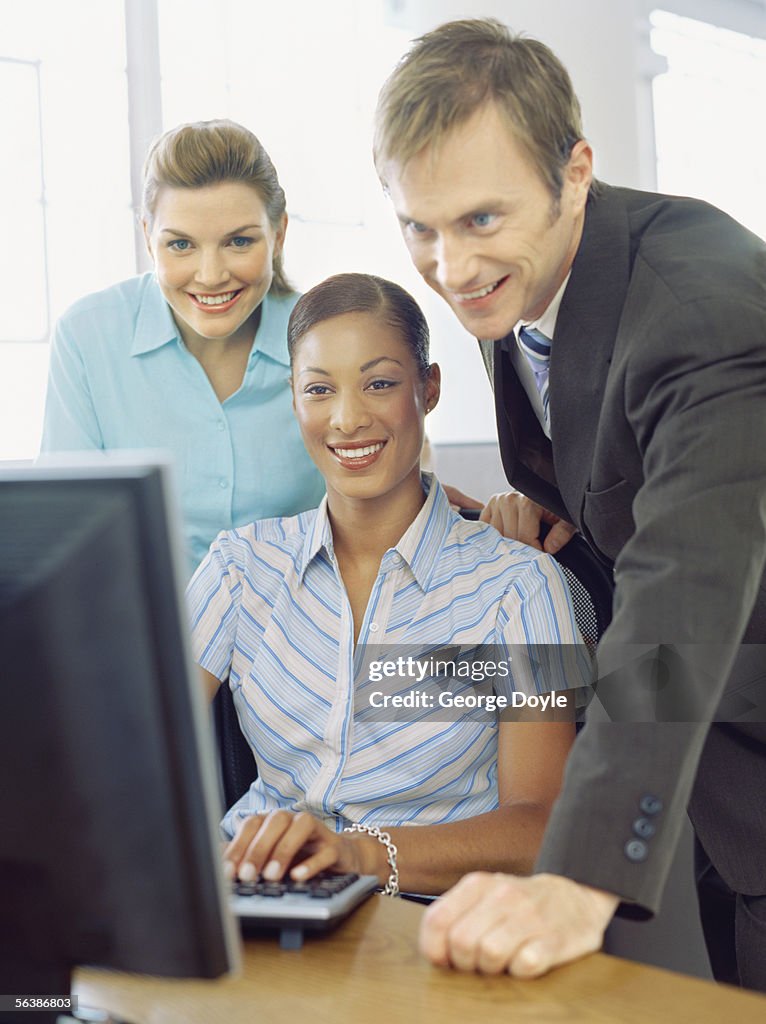 Two businesswomen and a businessman looking at a computer screen