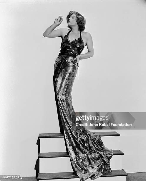 Portrait of actress Lili Damita standing on a high step wearing a long dress, for Paramount Pictures, 1932.