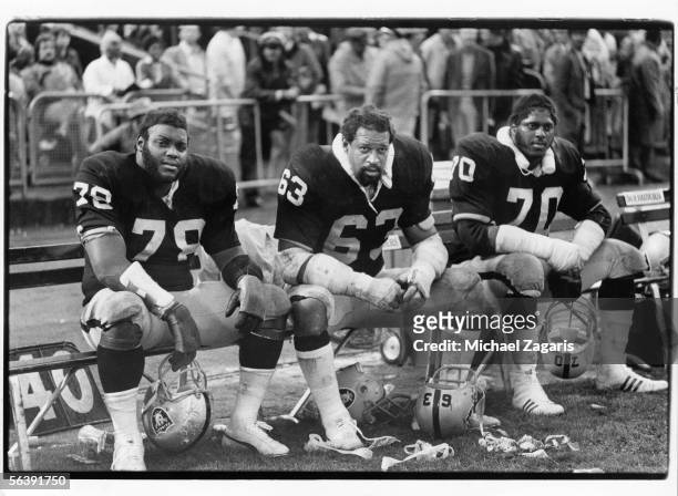 Offensive linemen Art Shell, Gene Upshaw and Henry Lawrence of the Oakland Raiders sit on the bench against the Minnesota Vikings at Oakland Alameda...