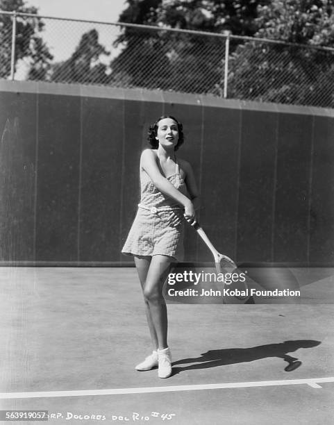 Actress Dolores del Rio pictured playing tennis on an outdoor court, for Columbia Pictures, 1937.