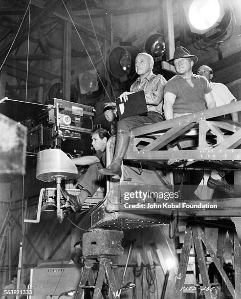 Filmmaker Cecil B DeMille sitting on a camera rig with members of his crew, on the set of the film 'Samson and Delilah', for Paramount Pictures, 1949.