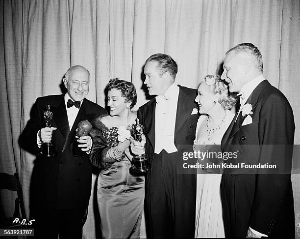 Filmmaker Cecil B DeMille holding his Best Picture Oscar for the film 'The Greatest Show on Earth', for Paramount Pictures, with a group of people...