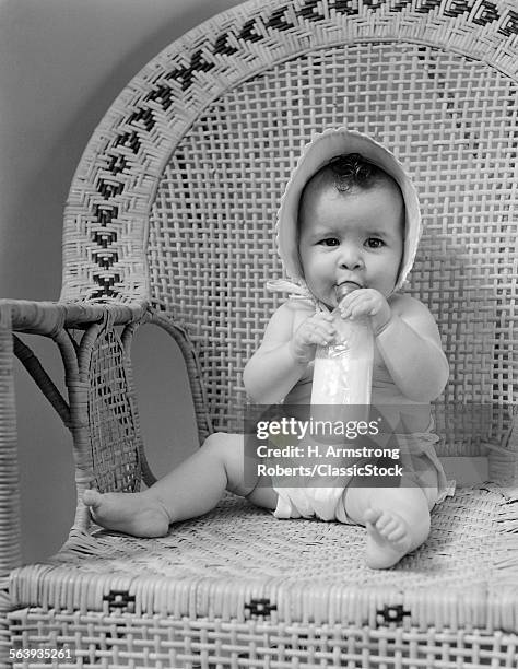 1940s BABY SITTING IN WICKER CHAIR SUCKING MILK BOTTLE