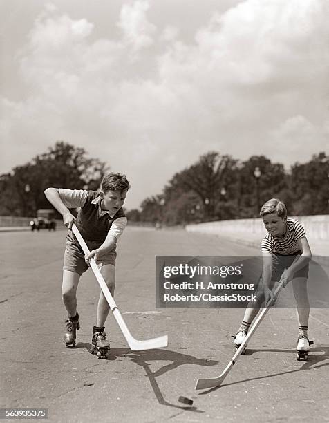 1930s 1940s 2 BOYS WITH STICKS AND PUCK WEARING ROLLER SKATES PLAYING STREET HOCKEY