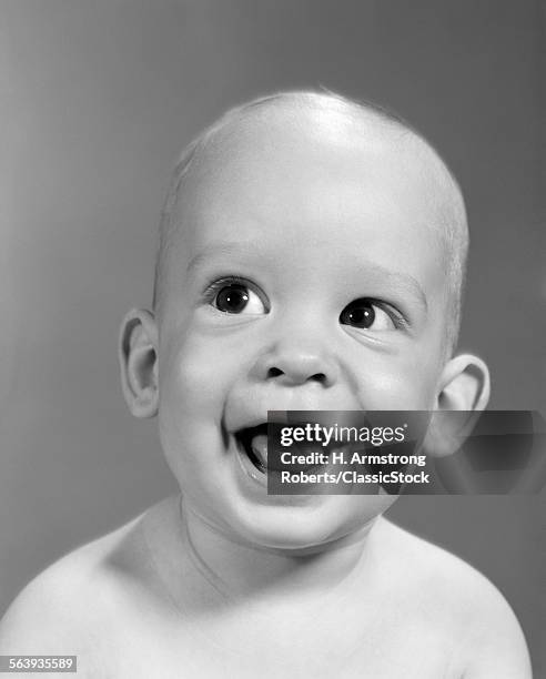 1960s CLOSE-UP PORTRAIT OF NEARLY BALD BABY SMILING WITH MOUTH WIDE OPEN LOOKING OFF TO THE SIDE