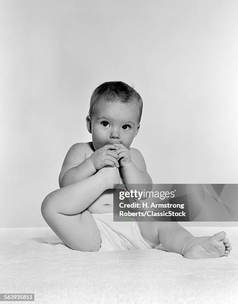 1950s 1960s BABY SEATED ON BLANKET BRINGING FOOT TO MOUTH
