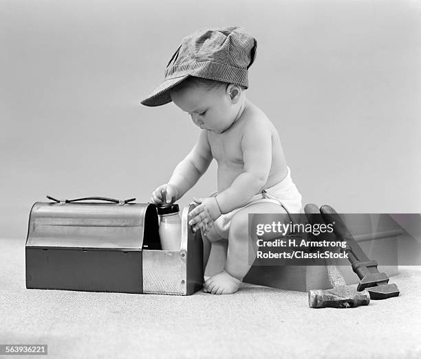 1940s BABY IN RAILROAD ENGINEER HAT PULLING MILK BOTTLE FROM LUNCH PAIL WITH HAMMER & WRENCH TOOLS AT SIDE STUDIO