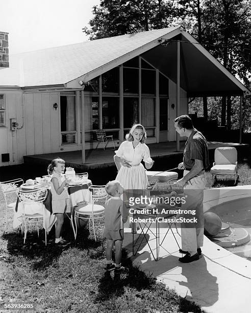 1950s FAMILY GRILLING HAMBURGERS BESIDE POOL IN BACKYARD COOKOUT