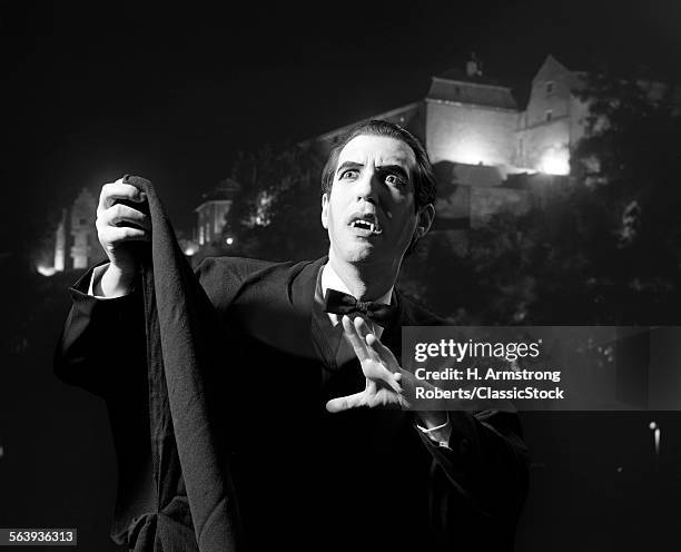 1970s HALLOWEEN NIGHTTIME PORTRAIT OF MAN WEARING CAPE AND FANGS DRESSED AS DRACULA THE VAMPIRE