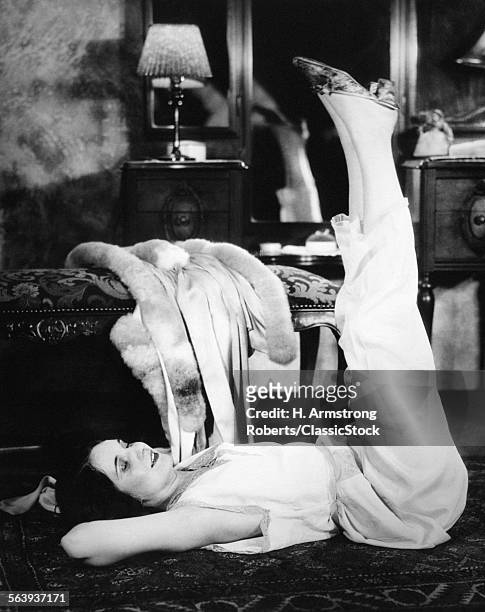 1920s 1930s WOMAN IN BEDROOM LYING ON FLOOR EXERCISING DOING LEG LIFTS