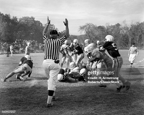 1960s CLOSE ACTION OF HIGH SCHOOL FOOTBALL GAME WITH BALL CARRIER BEING TACKLED & REFEREE SIGNALING A GOAL LINE TOUCHDOWN