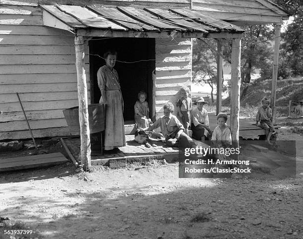 1930s 1940s FARM WOMAN WITH SIX CHILDREN ON PORCH OF CLAP BOARD FARM HOUSE