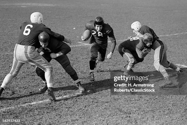 1940s 1950s FOOTBALL PLAYER RUNNING WITH BALL AS BLOCKERS DEFEND HIM