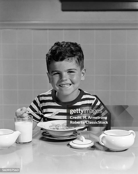 1940s 1950s SMILING BOY EATING BREAKFAST CEREAL LOOKING AT CAMERA