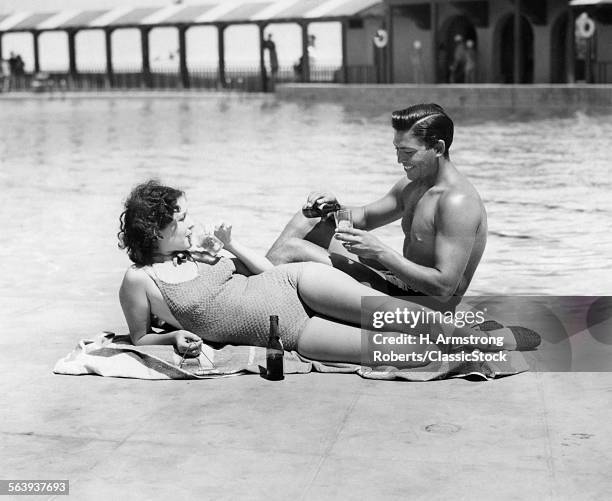 1930s 1940s COUPLE WEARING BATHING SUITS SITTING RELAXING POOL SIDE DRINKING BEER