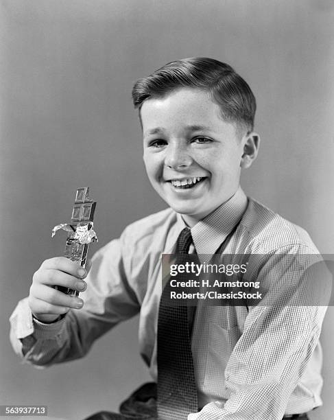 1940s SMILING BOY HOLDING EATING CANDY BAR CHOCOLATE LOOKING AT CAMERA