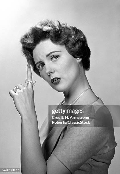 1950s CONCERNED WOMAN WITH REMINDER STRING KNOT TIED ON FINGER OF HAND TO HELP REMEMBER SOMETHING LOOKING AT CAMERA