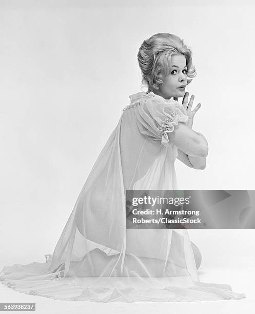 1960s PROFILE PORTRAIT OF BLOND WOMAN IN SHEER NIGHTGOWN KNEELING DOWN WITH HANDS PRESSED TOGETHER LOOKING AT CAMERA
