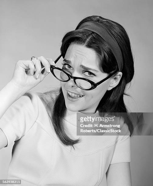 1960s WOMAN BRUNETTE LONG HAIR REMOVING PUTTING ON EYE GLASSES FUNNY FACIAL EXPRESSION LOOKING AT CAMERA