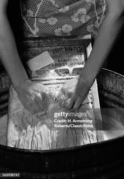 1920s 1930s 1940s CLOSE-UP OF WOMAN'S HANDS SCRUBBING CLOTHES ON WASHBOARD