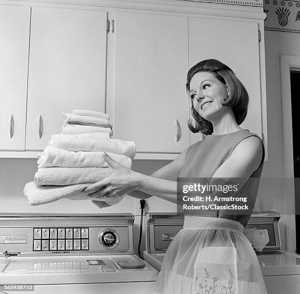 1960s SATISFIED WOMAN HOMEMAKER HOLDING FOLDED LAUNDRY