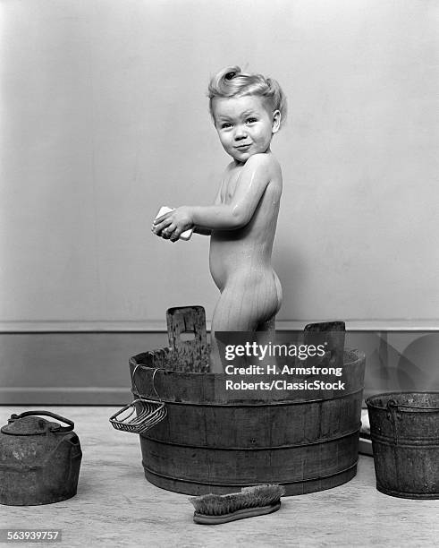 1940s LITTLE BLOND GIRL STANDING IN WOODEN WASHTUB HOLDING BAR OF SOAP TAKING A BATH