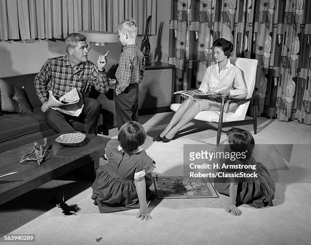 1960s FAMILY OF FOUR IN LIVING ROOM BOY IS BEING DISCIPLINED BY DAD SHAKING FINGER