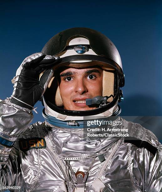 1960s PORTRAIT OF MAN IN SILVER ASTRONAUT SUIT SALUTING LOOKING AT CAMERA