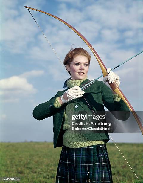 1960s 1970s SPORTS WOMAN ARCHER HOLDING BOW PREPARING TO DRAW ARROW