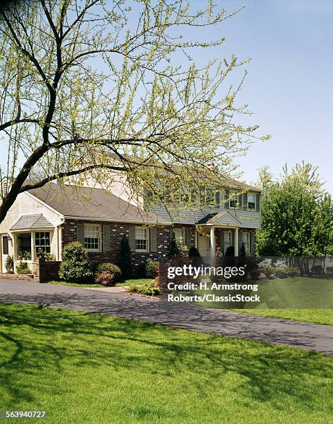 1970s HOUSE WITH BRICK SIDING AND BEIGE SHUTTERS IN THE SPRINGTIME