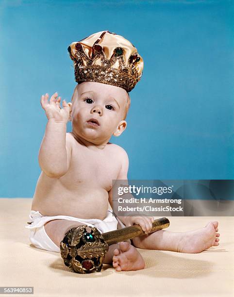 1960s BABY WEARING CLOTH DIAPER AND CROWN HOLDING A SCEPTER WAVING WITH ONE ARM RAISED LOOKING AT CAMERA