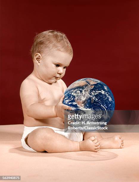 1960s SYMBOLIC ECOLOGY SERIOUS BABY WEARING CLOTH DIAPERS SITTING HOLDING LOOKING AT THE EARTH