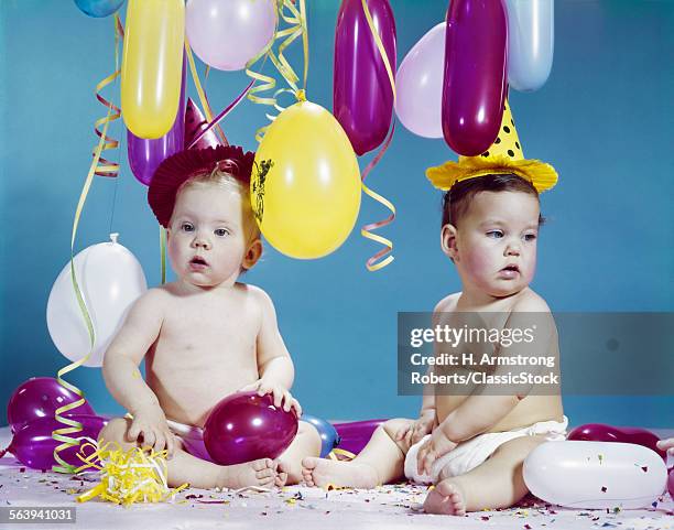 1960s TWO BABIES WEARING PARTY HATS WITH BALLOONS STREAMERS CONFETTI