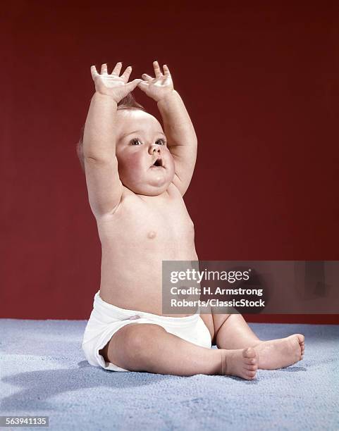 1960s BABY WEARING CLOTH DIAPER SITTING ARMS RAISED OVER HEAD