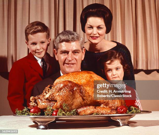 1960s PORTRAIT OF FAMILY FATHER MOTHER SON DAR LOOKING AT THANKSGIVING OR CHRISTMAS ROAST TURKEY
