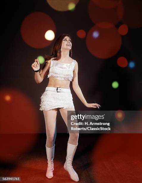 1960s YOUNG WOMAN DANCING AMONG LIGHTS WEARING MINI SKIRT AND FRINGED SHORT TOP