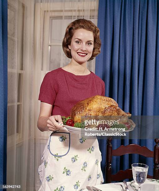 1960s SMILING WOMAN SERVING THANKSGIVING TURKEY DINNER